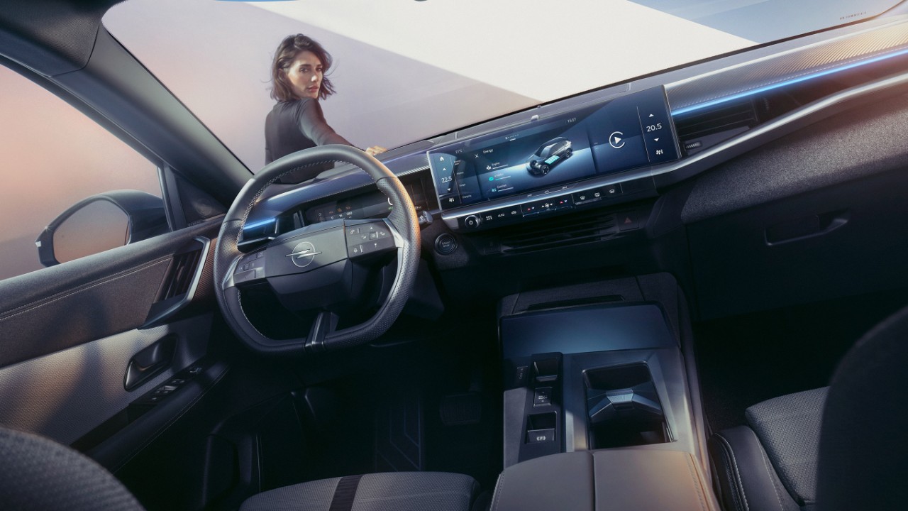 Primer plano del sistema de visualización de panel puro en un Nuevo Opel Grandland con una mujer apoyada en el coche y mirando al interior